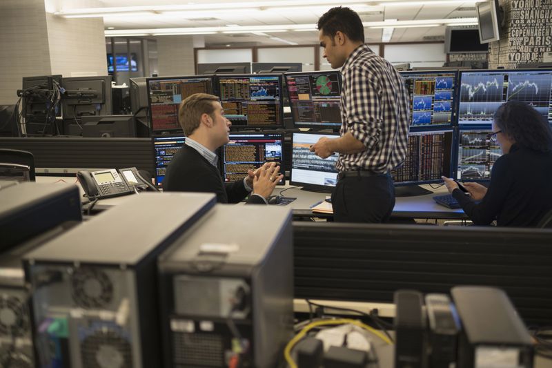 Traders in front of a bank of monitors