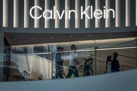 Shoppers walk past a Calvin Klein store beneath illuminated signage inside a modern shopping mall on May 20, 2025 in Chongqing, China