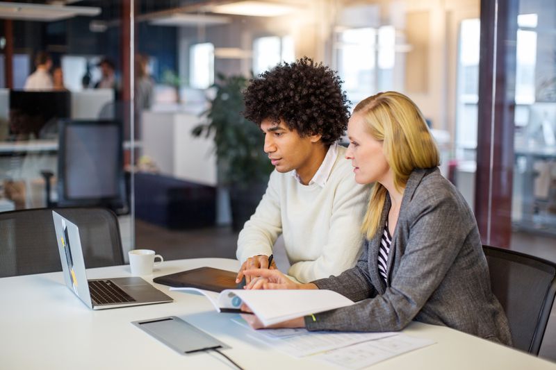 Two employees review documents in an office setting