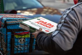 A person carries a Papa Johns pizza box on the street of New York City.