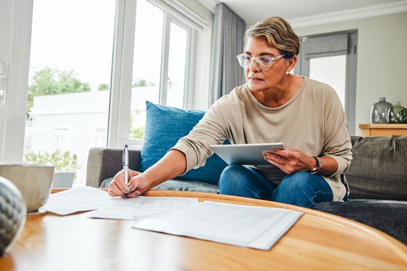 A woman signs documents on a coffee table.