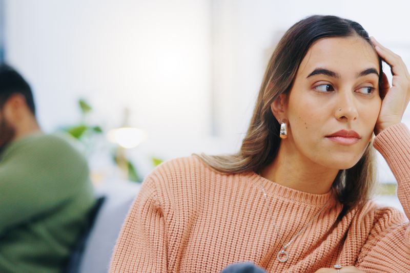 Woman staring into distance with partner in background. 