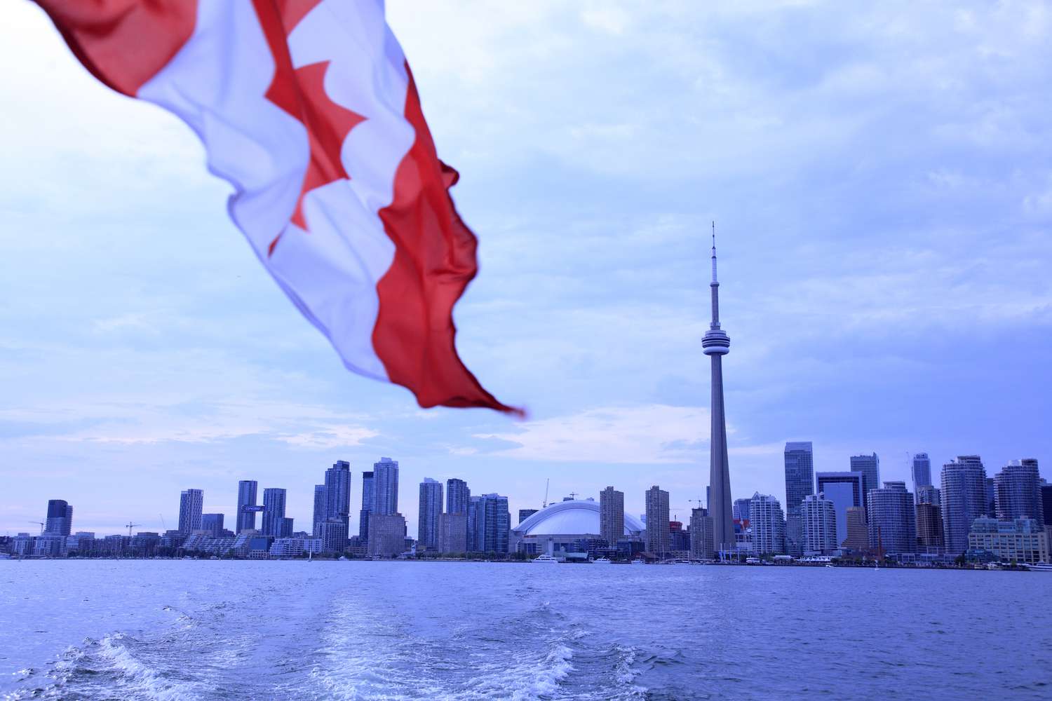 Skyline of Toronto with a Canadian flag in the foreground. 