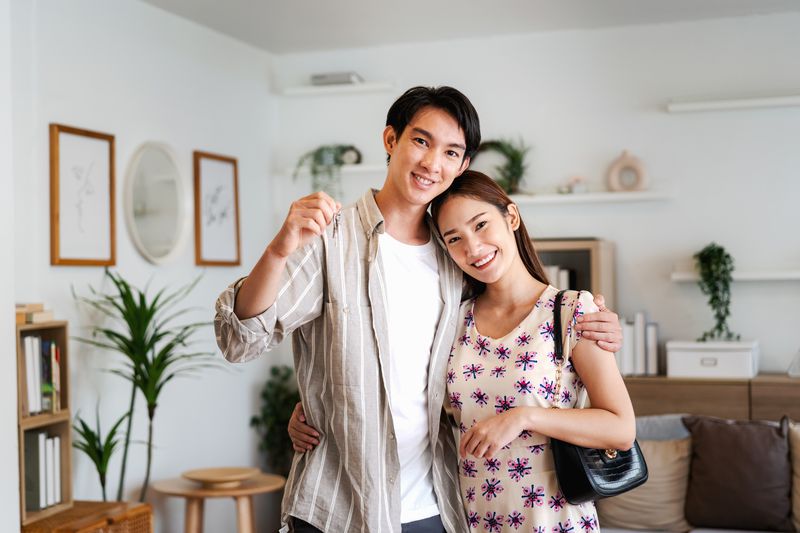 Young couple holding the keys to their newly purchased home in their living room