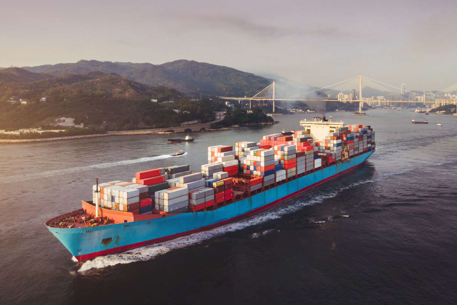 Container ship loaded with goods sailing away from a port