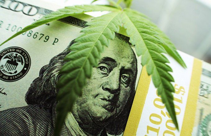 A 100 dollar bill and a marijuana leaf on top.