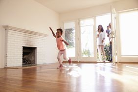 Aa family walks in the front door of a new home with a fireplace in the living room