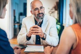 Two people meeting with a financial across a table in what appears to be a home.