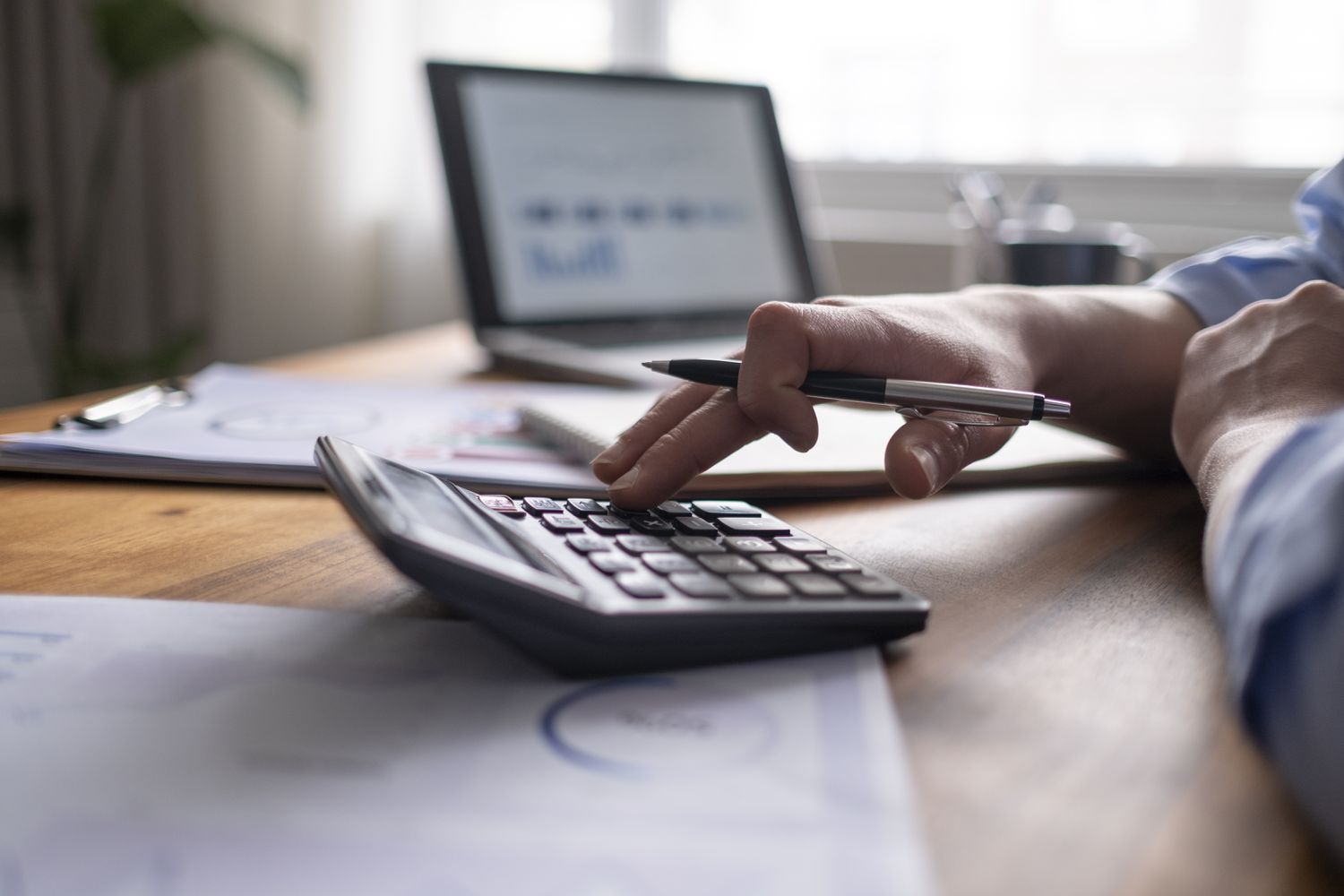 A person using a pen and calculator takes the FINRA’s Series 79 exam online.