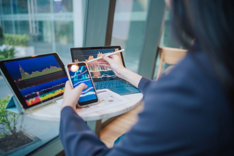Person analyzing stock charts on multiple devices at a desk