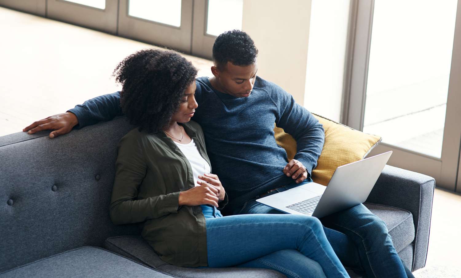 Young couple sitting on their sofa and looking at mortgage rates on a laptop