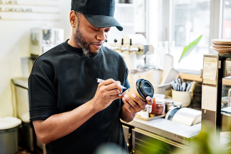A barista writing a name on a coffee cup