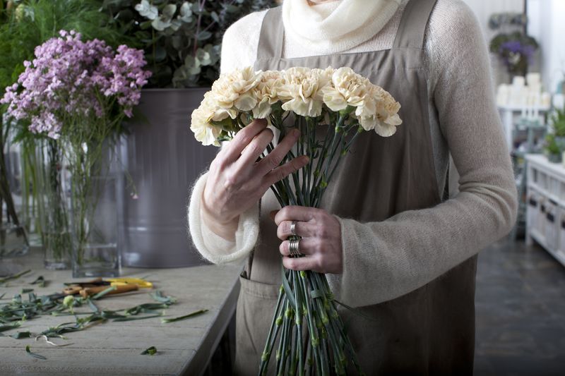 Close-up of a person working in a floral shop holding an arrangement of flowers in their hands
