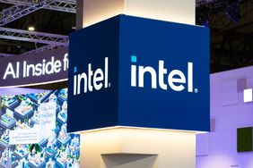 The Intel logo is seen on a blue sign on a pillar inside a conference hall.