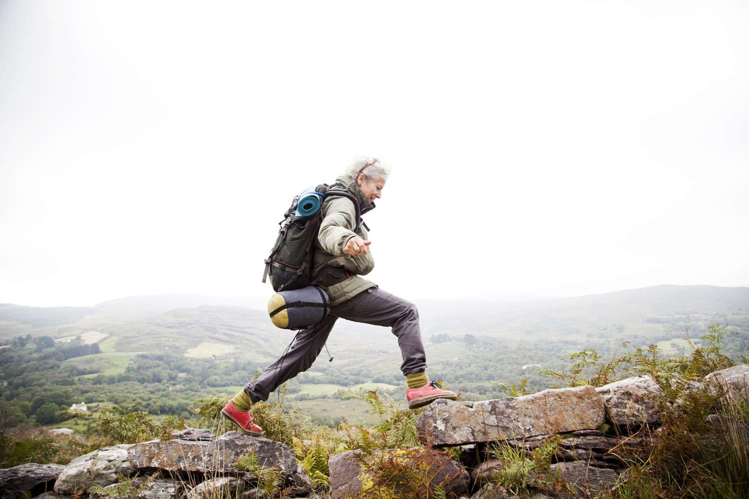 Older woman happily trekking in the mountains of ireland, solo travelor enjoying freedom and independence.
