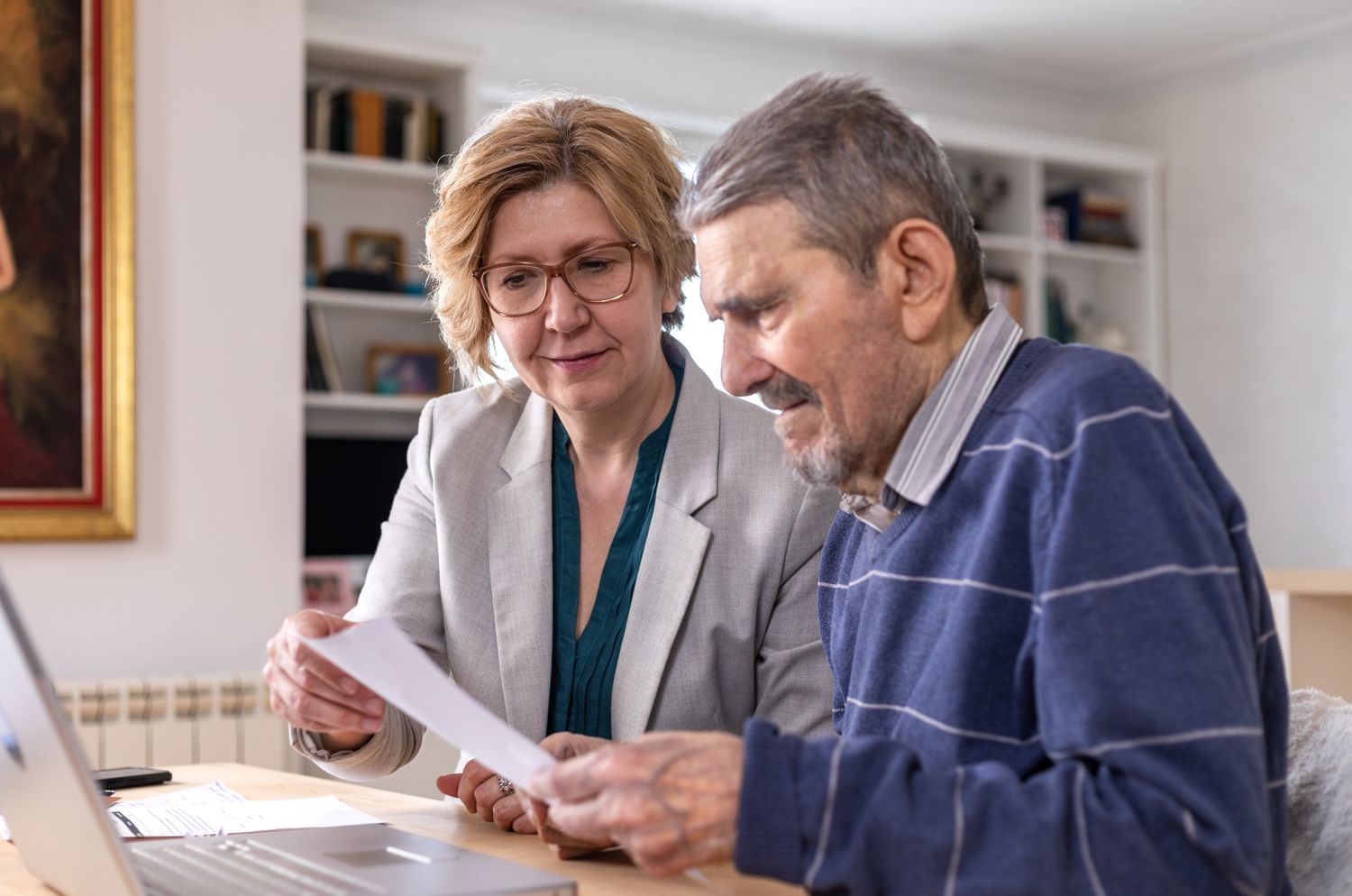 A daughter uses a laptop to help their father choose secondary beneficiaries for during estate planning.