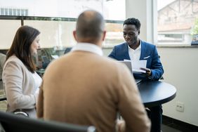 A financial advisor meeting with two people to discuss their portfolio.