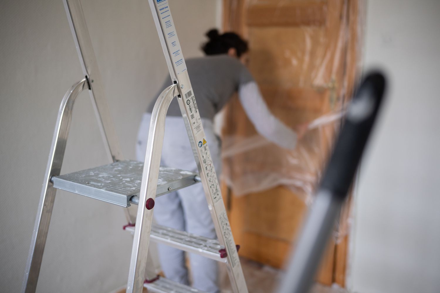 An image of a woman preparing a room in a home for painting. 