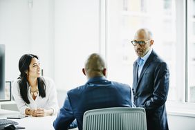 Mature businessman leading project meeting with colleagues in office conference room