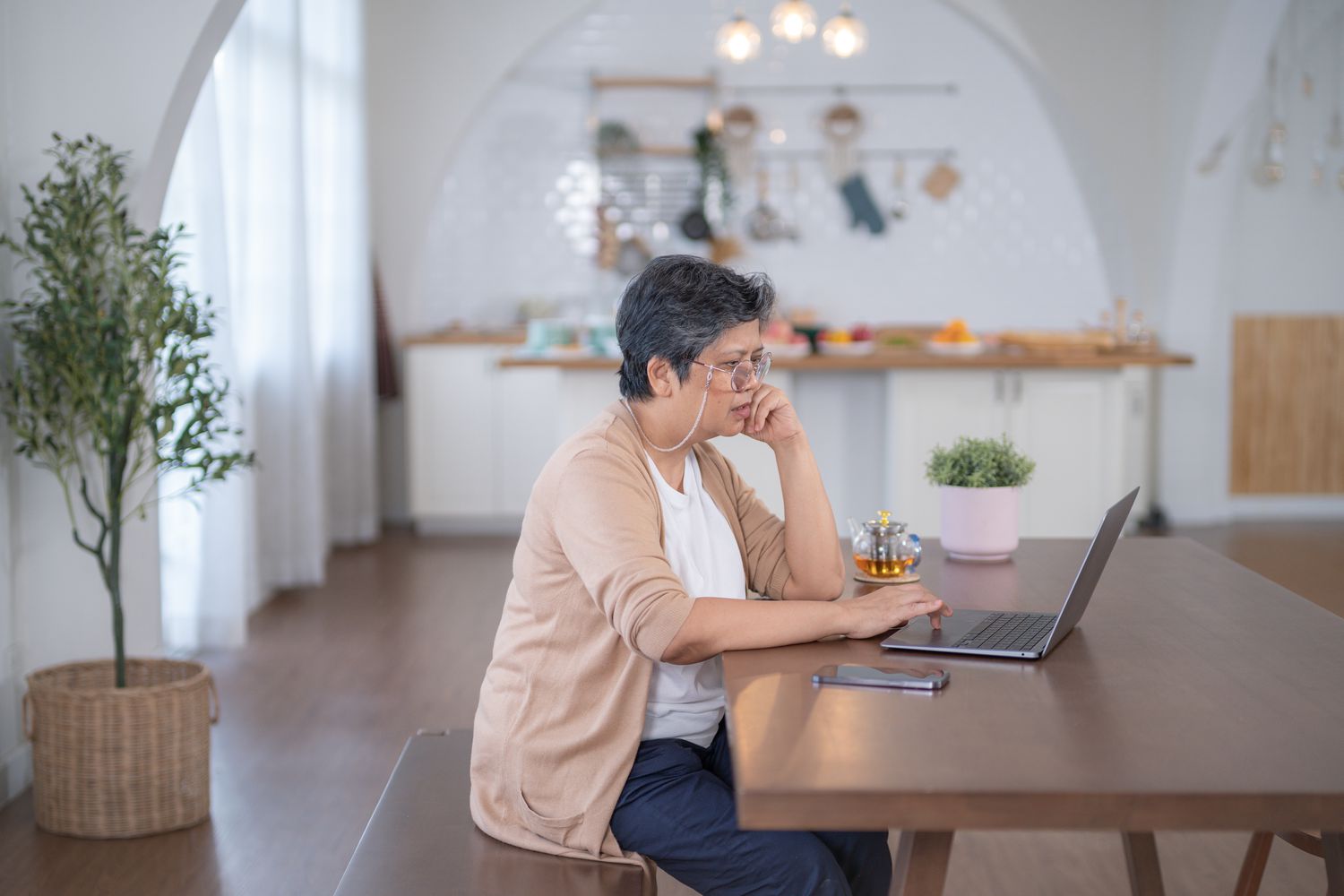 A woman sits at a table with a laptop