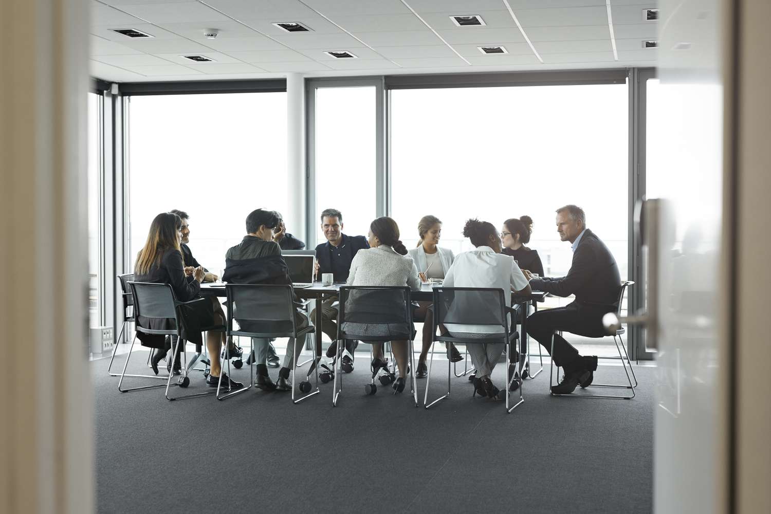 Co-workers having meeting with laptop in conference room