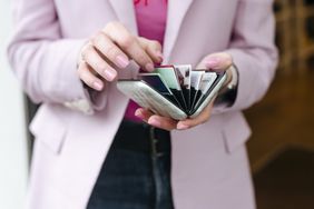 A person counting the number of credit cards within the cardholder. 