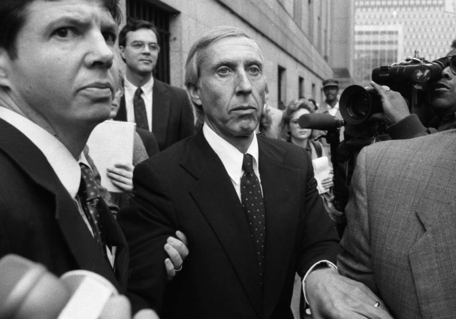 Ivan Boesky, surrounded by a crowd of people, leaves a courthouse after pleading guilty to a count of conspiracy.