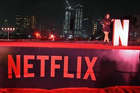 A woman poses for a photo near Netflix logo at a promotional event for the Netflix television series 'Heeramandi : The Diamond Bazaar' in Mumbai.