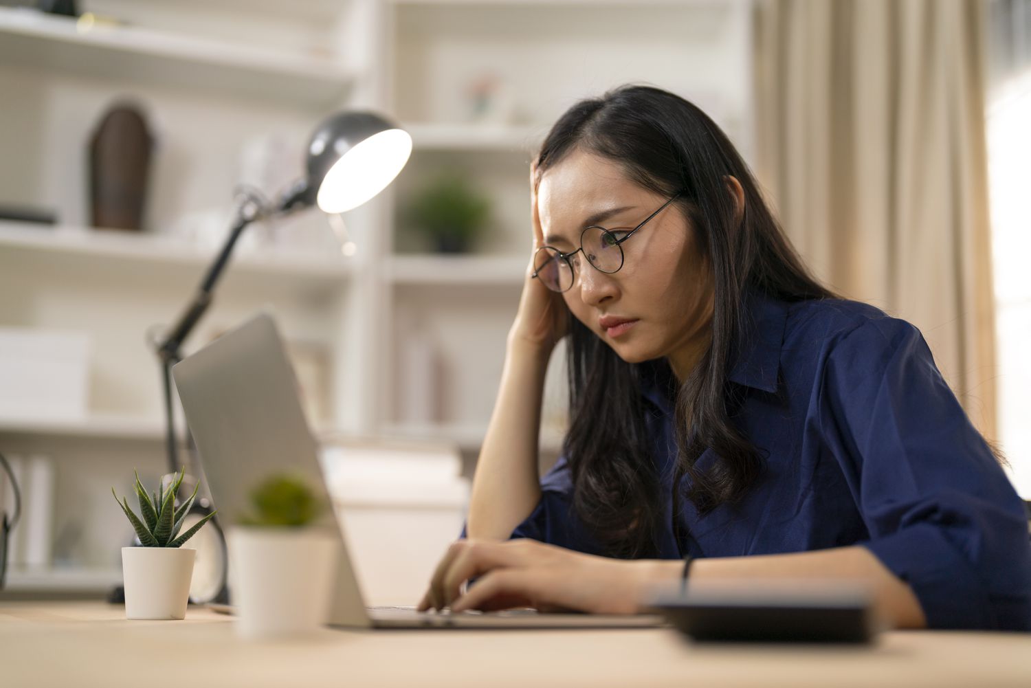 A woman using a laptop, looking concerned