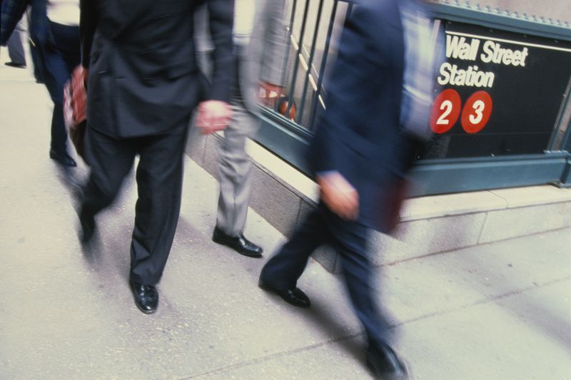 Businesspeople in suits passing Wall Street subway station