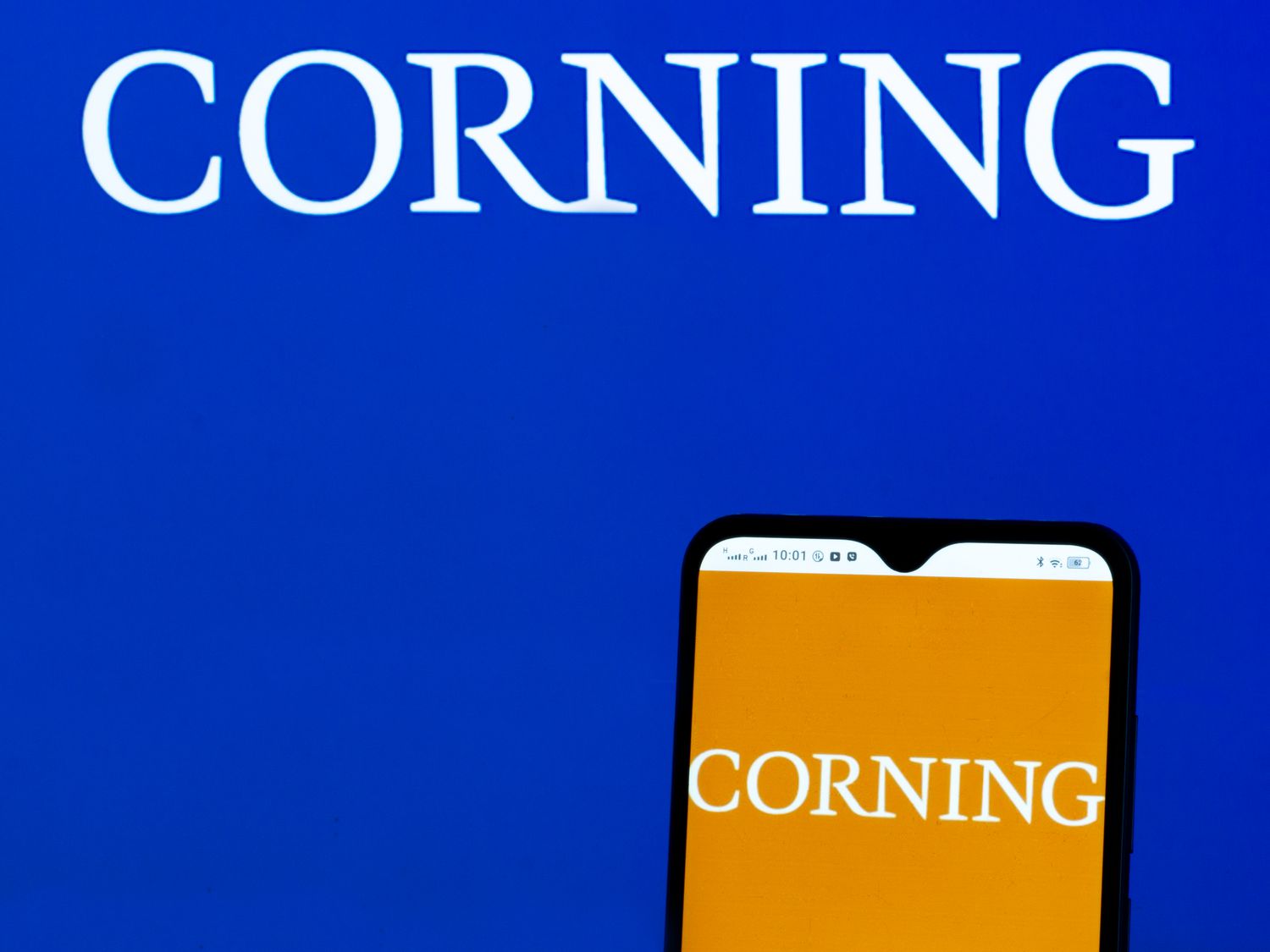 Corning logo displayed on a smartphone and in the background