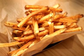 A container of French fries on a table. 