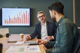 A financial advisor is speaking in a conference room with a younger person who is the client.