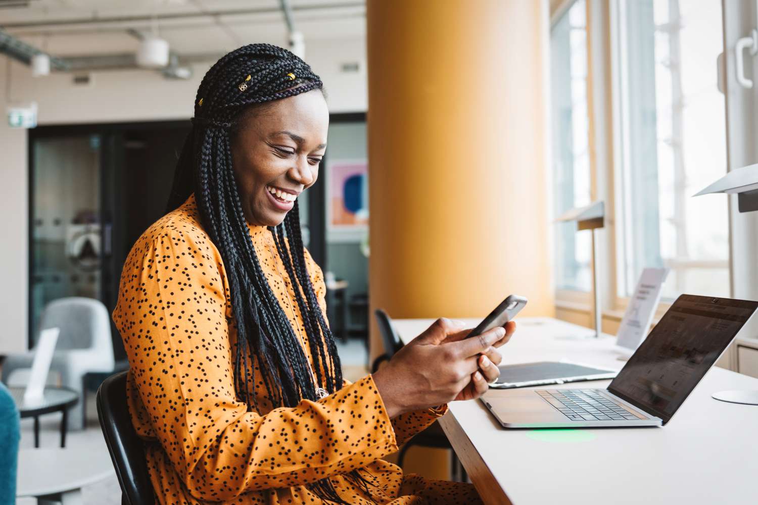 Smiling worker with a cell phone and a computer in an office