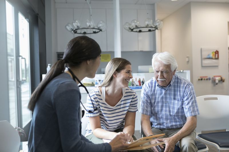 doctor talking with senior male patient in clinic waiting room