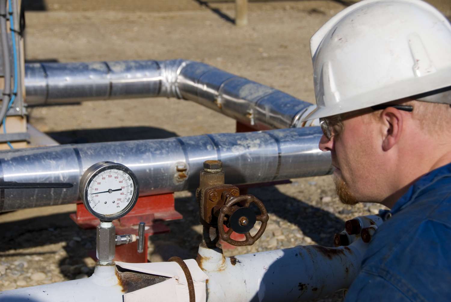 An engineer reads a pressure guage at an oil well using thermal injection to recover additional oil reserves.