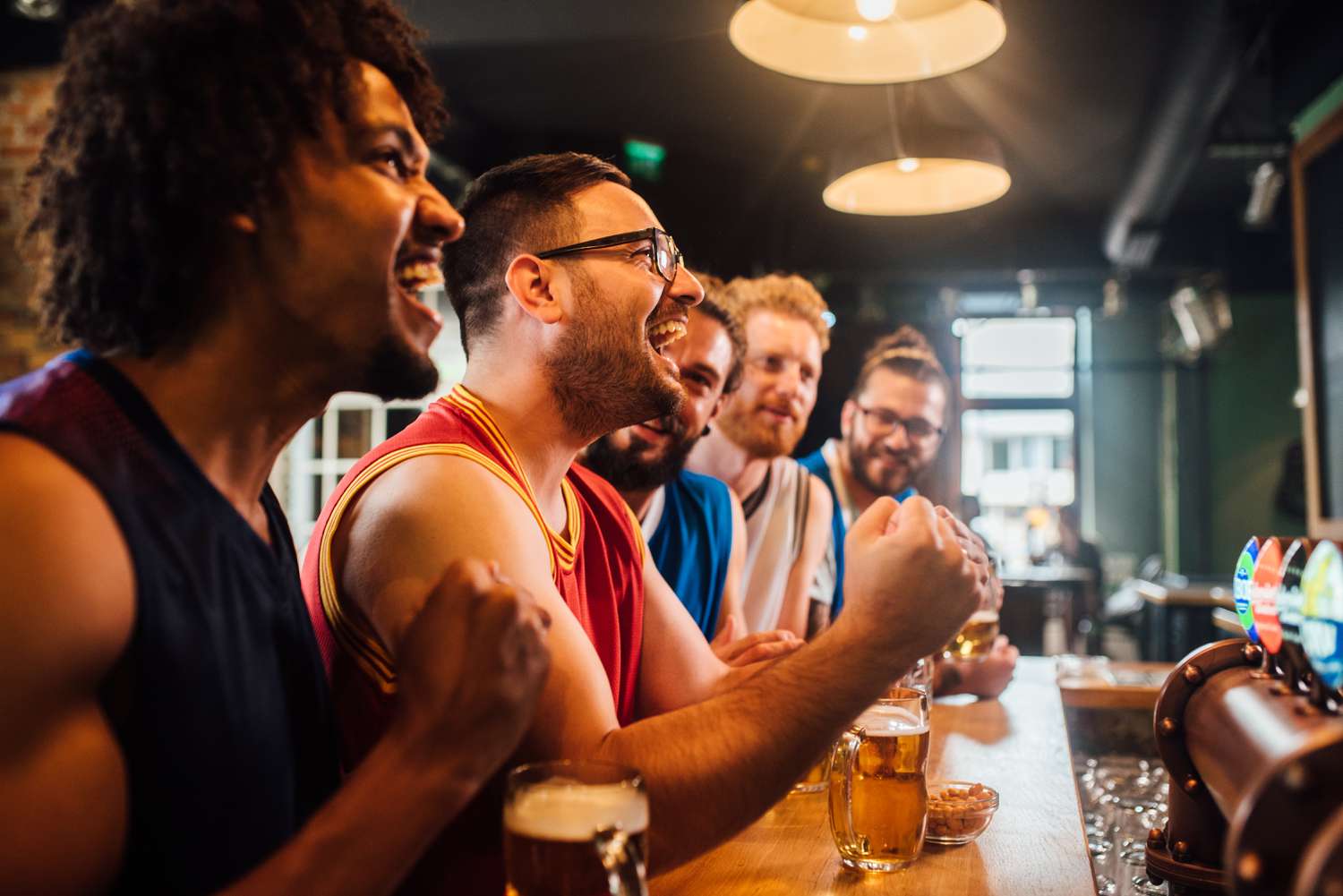 Young men with beers cheering at a bar