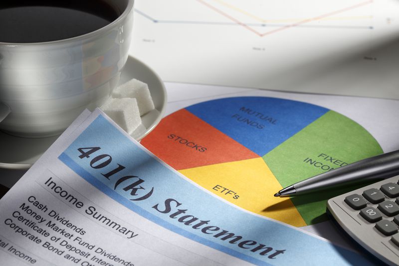 401(k) statement and pie chart next to a pen, calculator, and coffee mug