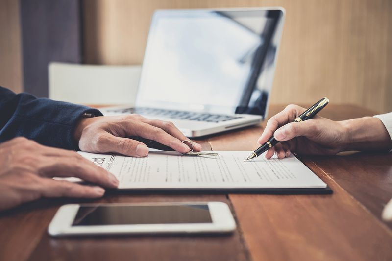 Midsection of Businessmen Signing Contract on Table