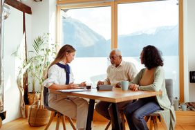 A couple meeting with a financial advisor in a room that overlooks a mountain
