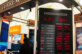 A currency exchange booth at an airport displays the current spot exchange rate for various currencies.