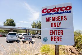 A white sign that says Costco Wholesale Members Only Enter Here is seen in front of a Costco gas station.