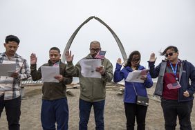 Immigrants take the oath of allegiance to the United States during a naturalization ceremony held in front of the "Gateway to the Arctic" whale bone sculpture on August 10, 2023 in Utqiagvik, Alaska. Located along the Arctic Ocean, Utqiagvik is the northernmost settlement in the United States. Formerly known as Barrow, the town of nearly 5,000 people is mostly populated by indigenous IÃÂ±upiat, but also with a growing immigrant population. This year U.S. Citizenship and Immigration Services (USCIS), who held the ceremony, launched a nationwide effort to bring immigration services to remote locations to help legal immigrants, often green card holders, to become American citizens. In the case of Utqiagvik, petitioners would have normally needed to take the two-hour flight to Anchorage, often multiple times, for citizenship appointments. The USCIS effort puts into effect the Biden Administration's Executive Order 14012, Restoring Faith in Our Legal Immigration Systems and Strengthening Integration and Inclusion Efforts for New Americans. The order, issued on February 2, 2021, instructs U.S. government agencies to promote citizenship through naturalization, improve the naturalization process overall and reduce wait times for applicants. It also revoked a Trump-era memorandum designed to slow and ultimately restrict legal immigration.