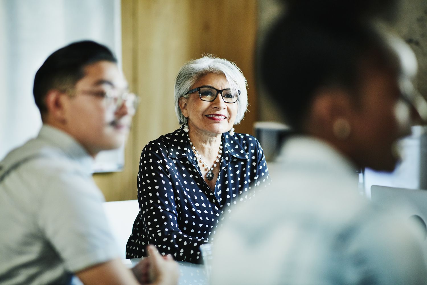 Smiling female business owner listening during presentation during meeting in office conference room