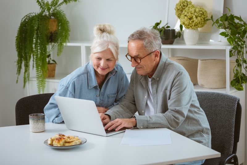 Older couple sitting in their kitchen and looking at mortgage rates on a laptop
