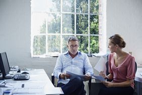 A father sits in a home office and discusses making a large withdrawal from a retirement account with their daughter.