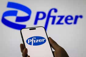The Pfizer logo is displayed on a smartphone screen in front of a larger Pfizer logo