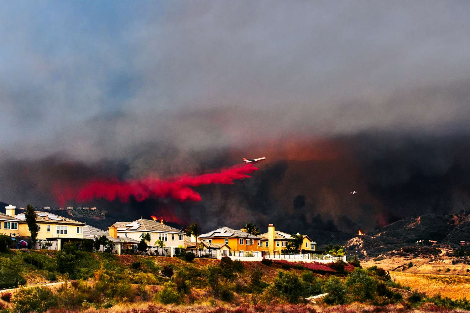 Homes threatened by a wildfire in the background