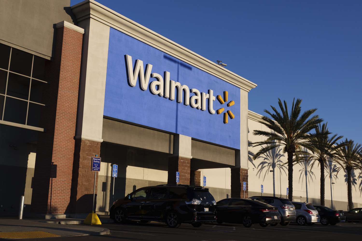 Cars are parked outside a Walmart store, with the company's logo seen above.