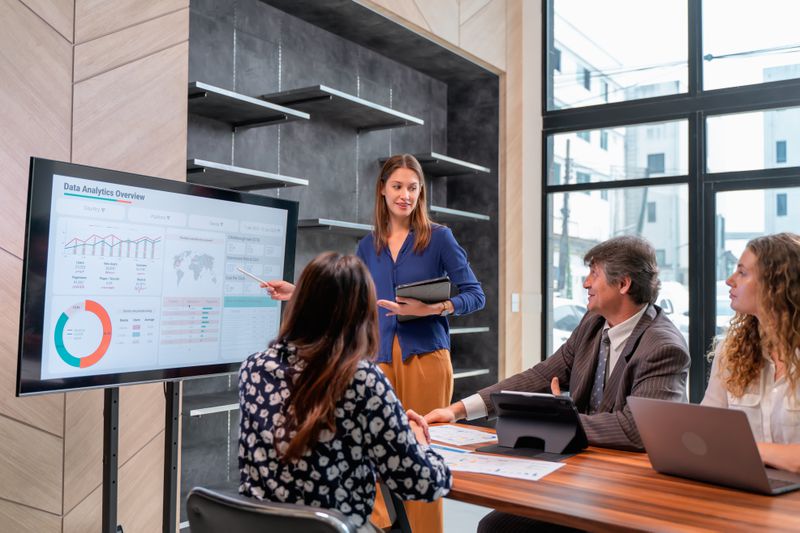 Woman giving presentation in office meeting room to colleagues